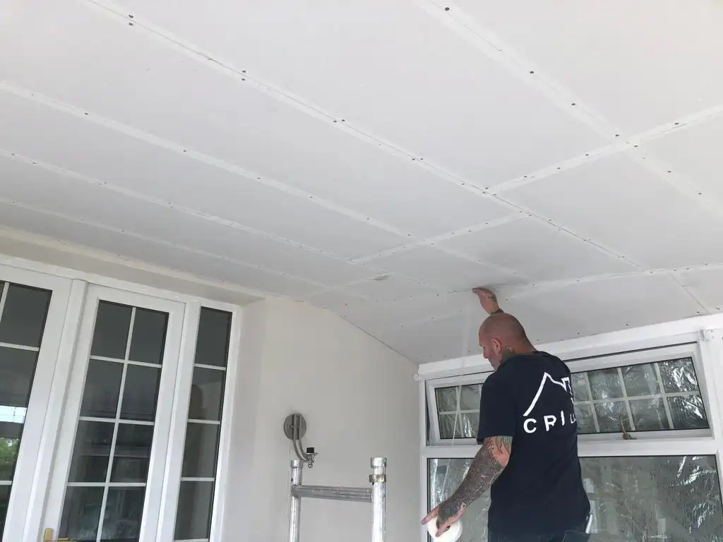 Man working on plastered conservatory roof insulation fitting Scotland
