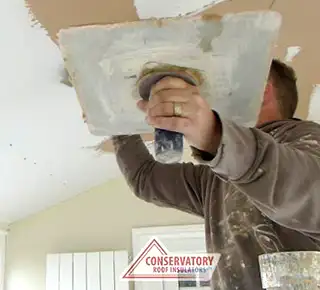 person skimming conservatory ceiling after insulation process